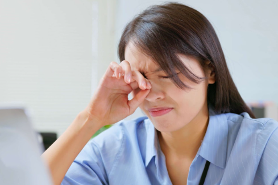 Woman rubbing her eyes due to eye strain while working on a computer